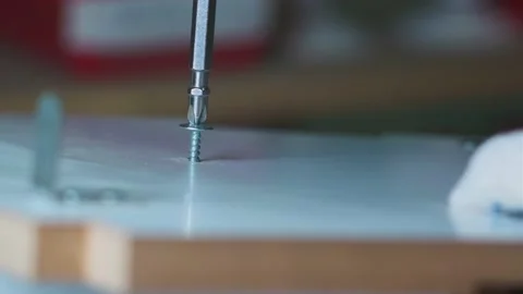 A man in gloves is screwing a self-tapping screw into a piece of wood close-up. Stock Footage 237308556