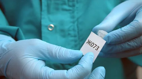 Man glues marker on tube with sample for coronavirus test Stock Footage 146769075