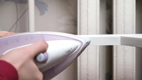 A man glues white melamine edging to raw edge of wood chipboard furniture. Stock Footage 169110573
