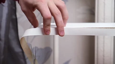 A man glues white melamine edging to raw edge of wood chipboard furniture. Vídeos de archivo 169110618
