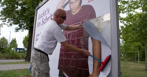 Man gluing a billboard on prevention of spreading venerial diseases, Germany 4K Stock Footage 119087630