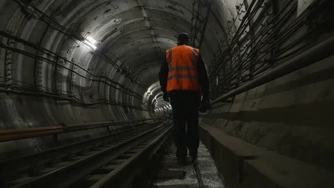 Man goes along the railway tracks in subway tunnel Stock Footage