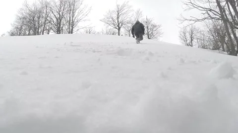 A Man Goes Down in the Snow From a Hillside Stock Footage 60604096