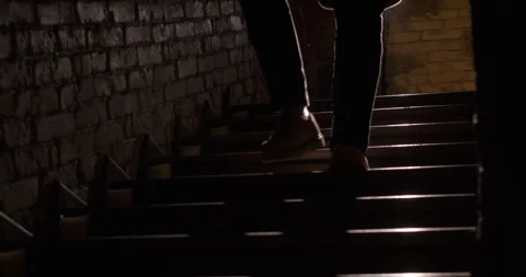 Man goes down stairs. Close up of legs stepping down stairs. Silhouette shot Stock Footage 256930925