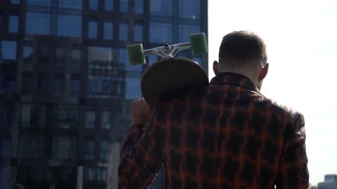 Man goes forward, holding longboard behind his back Stock Footage 130141379