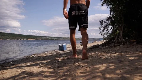 A man goes to the fridge by the river to get a cool drink Stock Footage 114631165