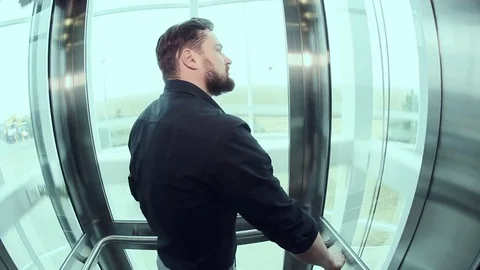 Man goes up into a glass elevator Stock Footage 73469953