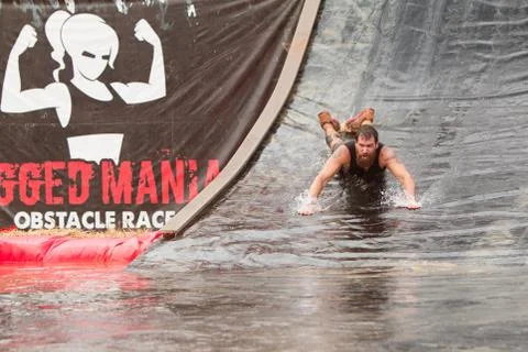 Man Goes Headfirst Down Water Slide In Obstacle Course Race Foto stock