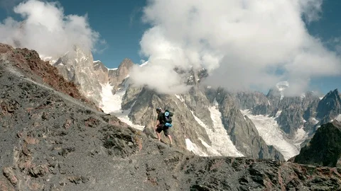 A man goes uphill, against the backdrop of Ushba Stock Footage 116616155