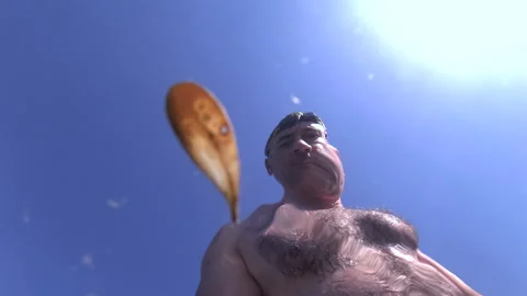 Man with goggles on his head resurfacing from the water, seen from an underwater Stock Footage 339793953