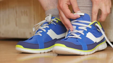 Man is going to do sports work out - tying the laces on sneakers Stock Footage 63733800