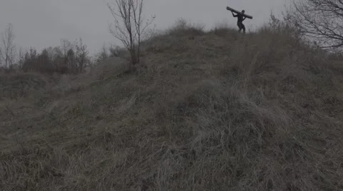 Man going downhill with a log on the shoulders (BMCC 2.5K - 2400x1350) Video stock 47945322