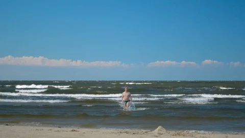 Man going out from the water on the beach after swimming in stormy sea ocean 스톡 동영상 92013467