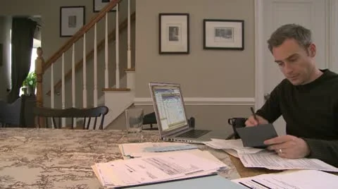 A man going over his bills on his dining room table (1 of 3) Stock Footage 10564897