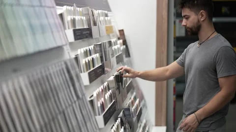 Man going to paint chip display and picking up brochure in hardware store Stock Footage 281175327