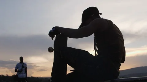 Man on going rollerblading sitting on a bench in a park 스톡 동영상 113113036