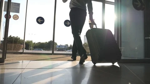 Man going through glass automatic door to the street and roll suitcase on wheels Stock Footage 79964787