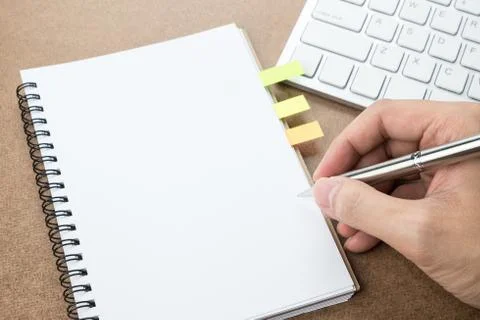 A man is going to write something on the blank notebook page. Stock Photos