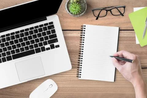 A man is going to write something on the blank notebook page. Stock Photos