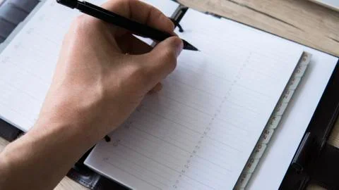 Man is going to write something on his notebook. Top view, flat lay. In Search Stock Photos