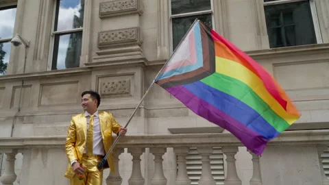 Man in Gold Suit Flies Progress Pride Flag at Pride in London LGBTQ Parade Stockbeeldmateriaal 200733336