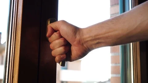 A man by the golden handle opens a brown plastic window Stock Footage 118090145