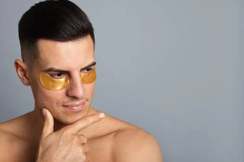 Man with golden under eye patches on grey background. Space for text Stock Photos