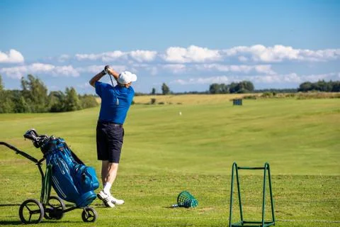 A man on a golf course hitting the ball towards the hole space for text Stock Photos