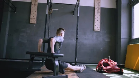 Man in good shape and condition doing triceps dip exercise on bench in gym. Stock Footage 119829141