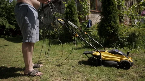 The man got tangled in the wires from the electric lawn mower Stock Footage 108460211