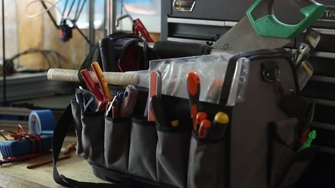 Man Grabbing a Screwdriver from His Tool Bag inside a Workshop Stock Footage 98966343