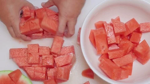 Man Grabs Chunks of Watermelon and Sets Them in a White Serving Bowl Stock Footage 79045408