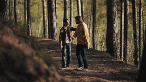 Man grabs his bearded friend shoulder while arguing in woods Stock Footage