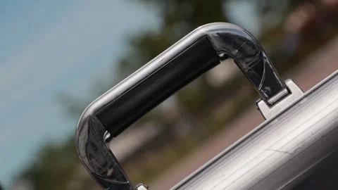 A man grabs hold of the handle of a stainless steel briefcase and picks it Video stock 246917956