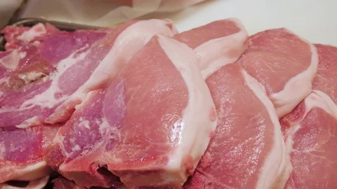Man Grabs a Pork Chop From a Stack of Meat Vidéo 71591370
