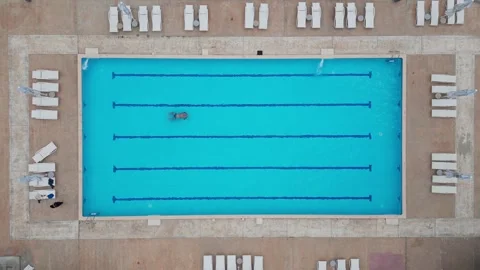 A man gracefully glides through an open air pool, creating ripples that dance in Stock Footage 242607251