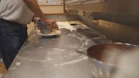 Man grates hard cheese with grater. Chef makes a filling on professional kitchen Video stock 100743311