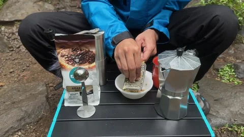 Man Grating Fresh Ginger Root Outdoors on Camping Table, Medium Shot Stock Footage 324850656