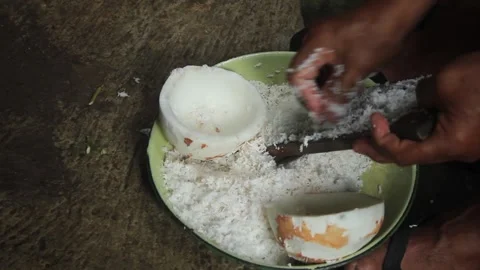 A man grating an old coconut with a traditional coconut grater to extract t.. Stock Footage 274385350