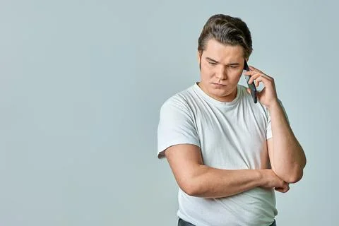 A man on a gray background is talking on the phone Stock Photos