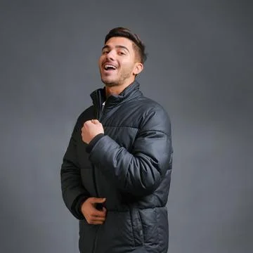 Man on a gray background is warmly dressed in a black down jacket Stock Photos