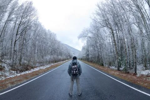 The man in gray with a backpack standing in the center of the gray road in a  Stock Photos