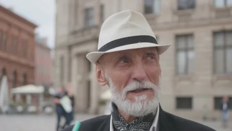 Man with gray beard and blue eyes talks against buildings Stock Footage 150776066
