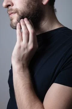 A man with a gray beard suffers from itching and rash on his cheeks Stock Photos