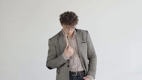 A man in a gray jacket and glasses stands in a white room and meditates Stock Footage 124941899
