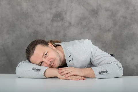 A man in a gray suit lay down on his arm. Stock Photos