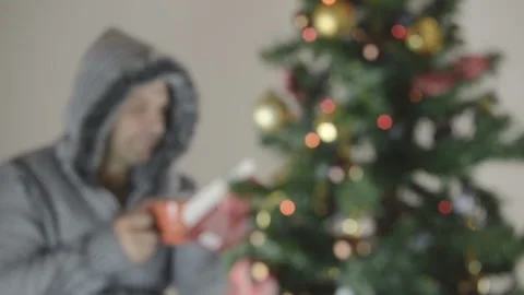 A man in a gray sweater drinks a hot drink. He enthusiastically reads the book Vídeo Stock 94852958