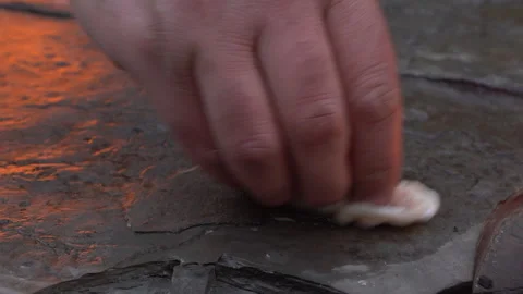 Man Greasing Hot Stone Over Campfire. Heated Stone for Outdoor Cooking Video stock 303661291