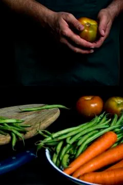 Man with green apron presenting vegetables and garden vegetables. Stock Photos