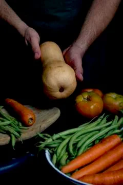 Man with green apron presenting vegetables and garden vegetables. Stock Photos